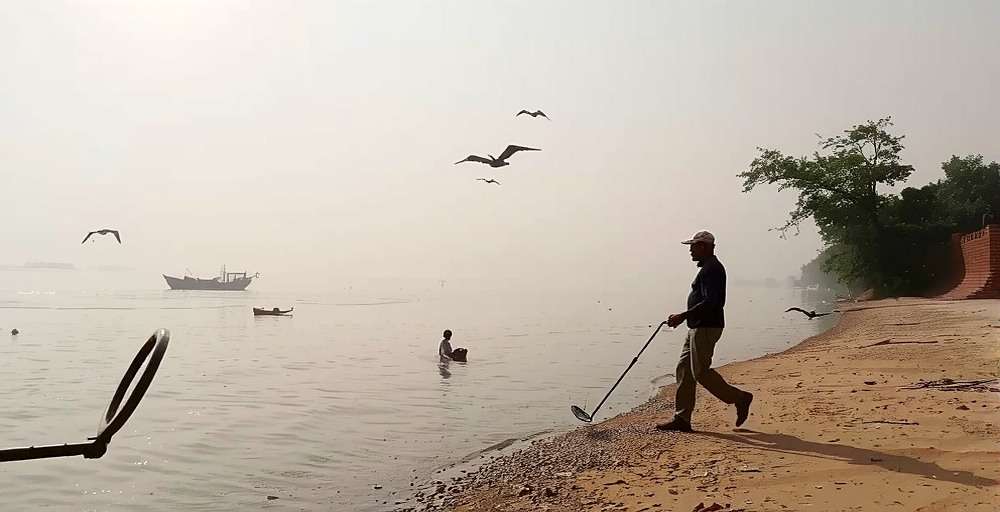 Shore exploration in Ganga Gold Grabbers Ganga Gold Grabbers player using a metal detector along the riverbank